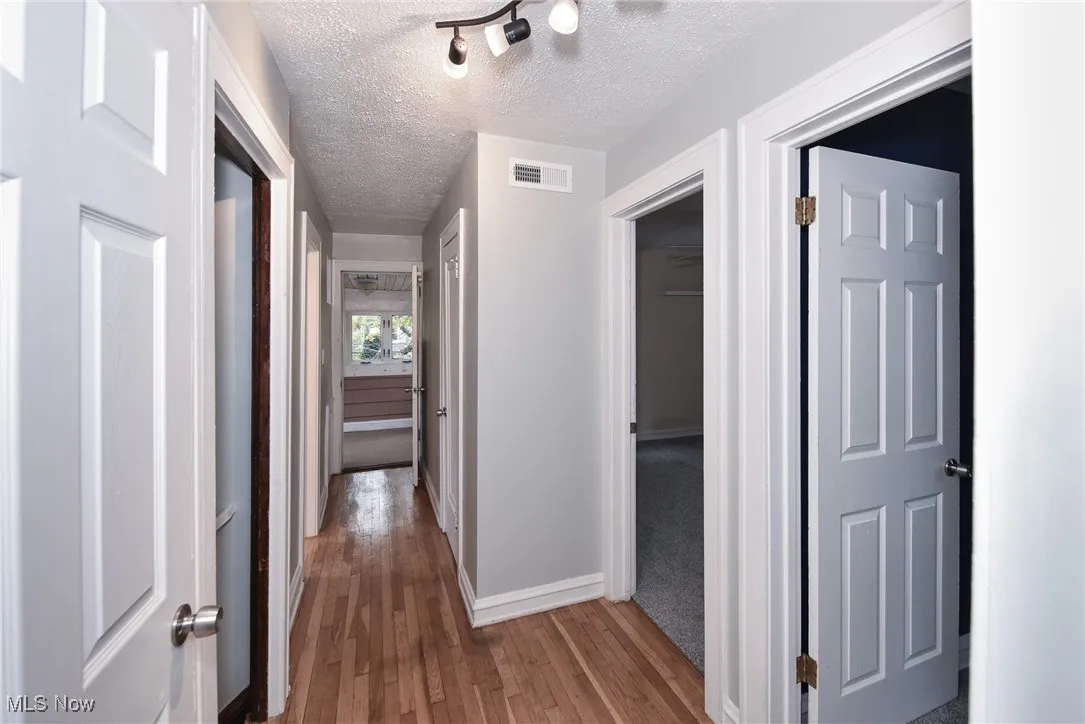 Corridor featuring a textured ceiling and dark wood finished floors