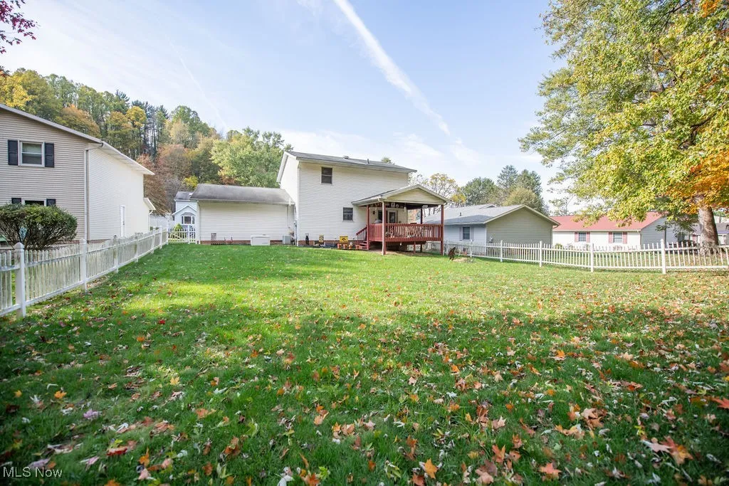 View of back of home with deck and fenced in yard