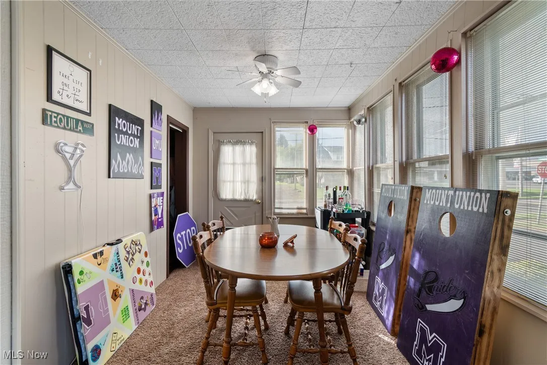 Dining room with wood walls, carpet, and ceiling fan