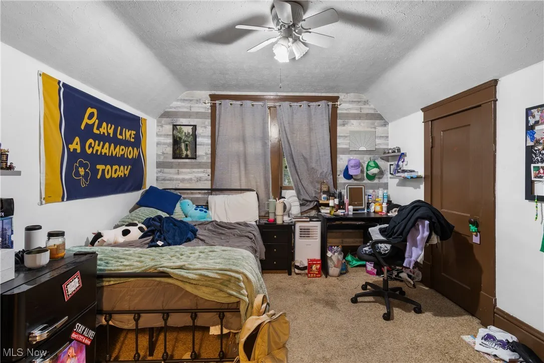 Bedroom with a textured ceiling, carpet floors, lofted ceiling, ceiling fan, and an office area
