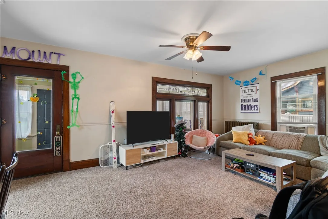 Carpeted living area featuring a ceiling fan