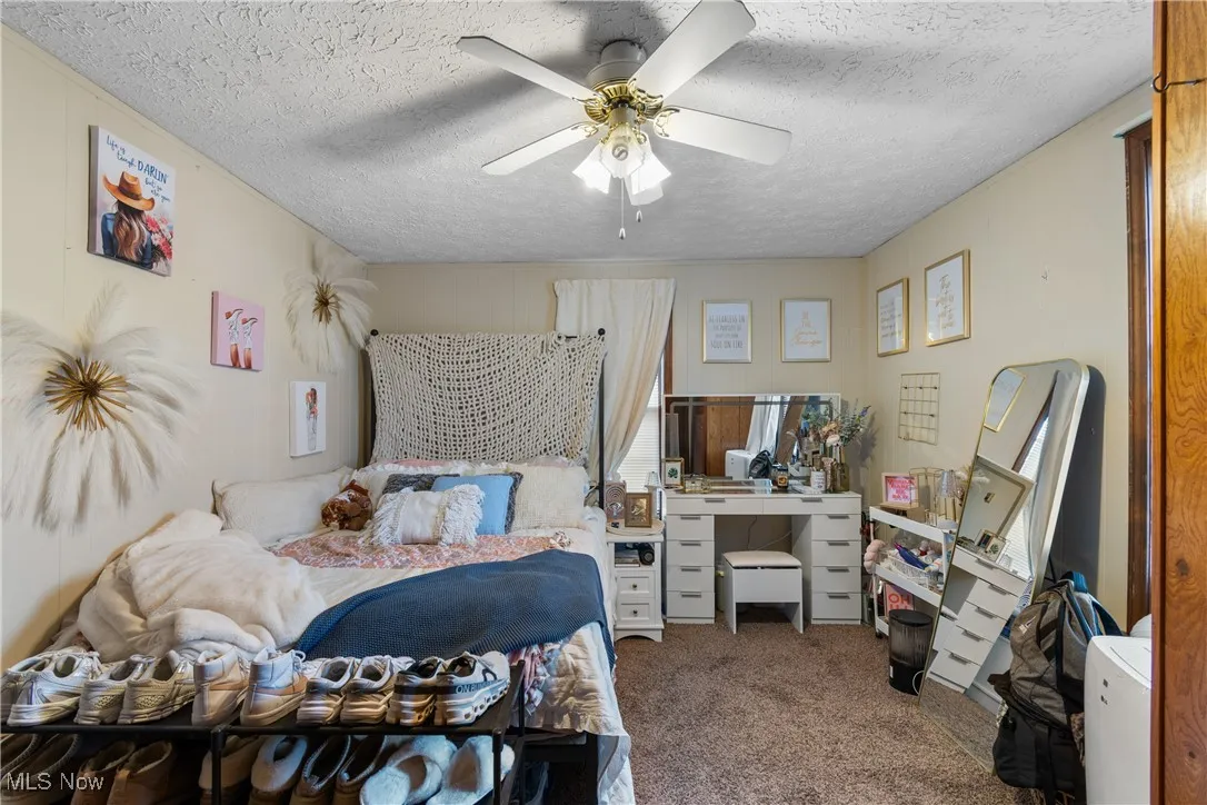Carpeted bedroom featuring a ceiling fan and a textured ceiling