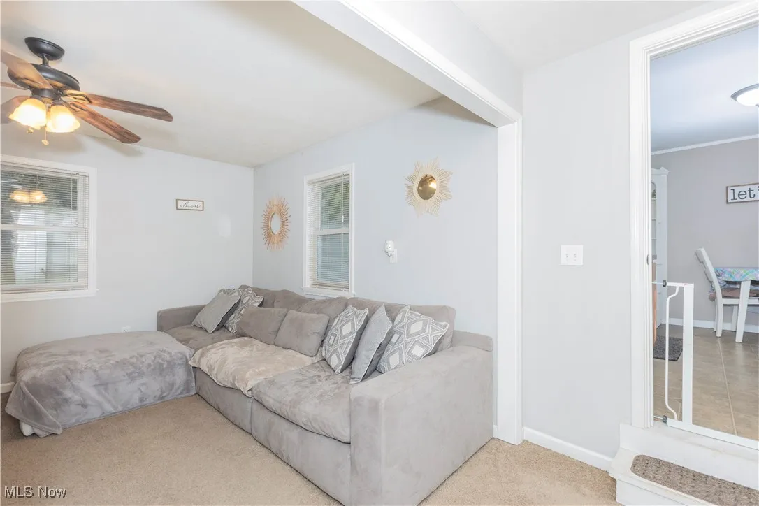 Carpeted living area featuring baseboards and ceiling fan