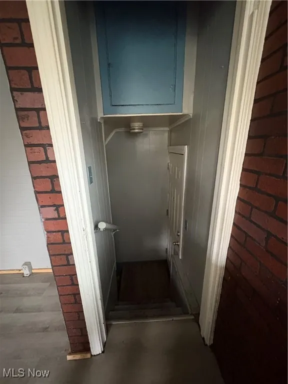 Stairway featuring brick wall and wood finished floors