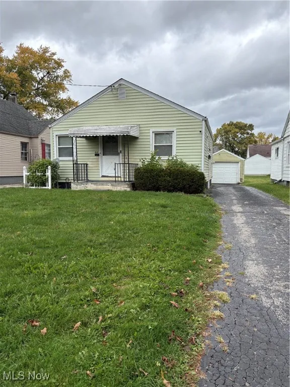 View of front of house with a front lawn, a garage, an outbuilding, and driveway