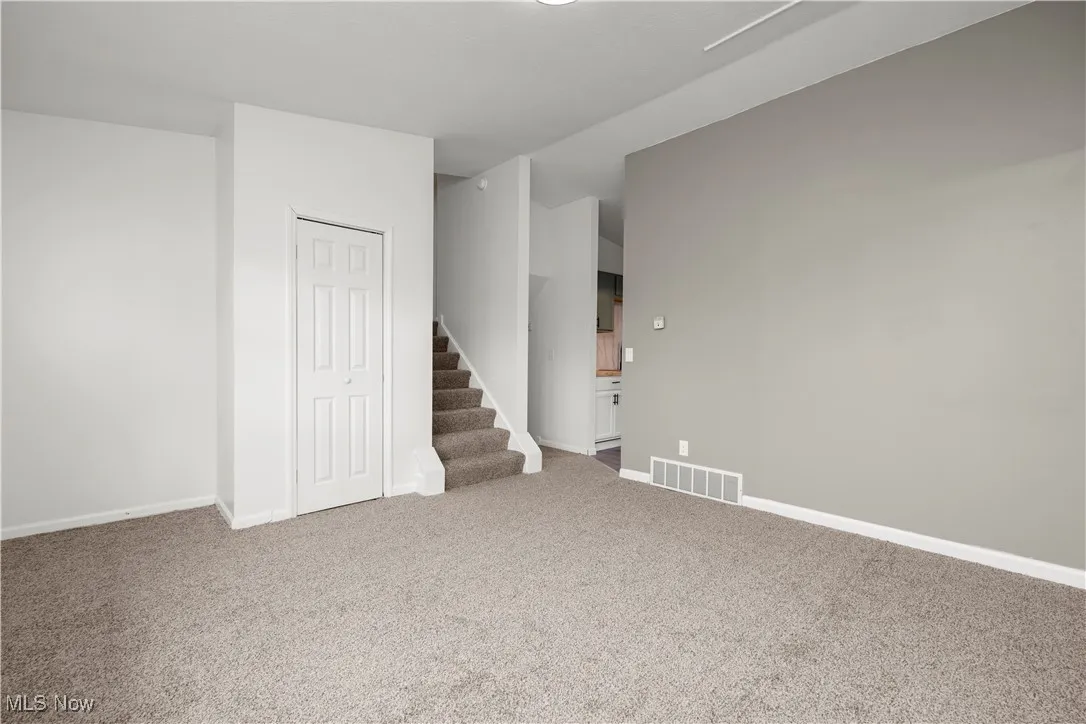 Empty room featuring stairs and carpet