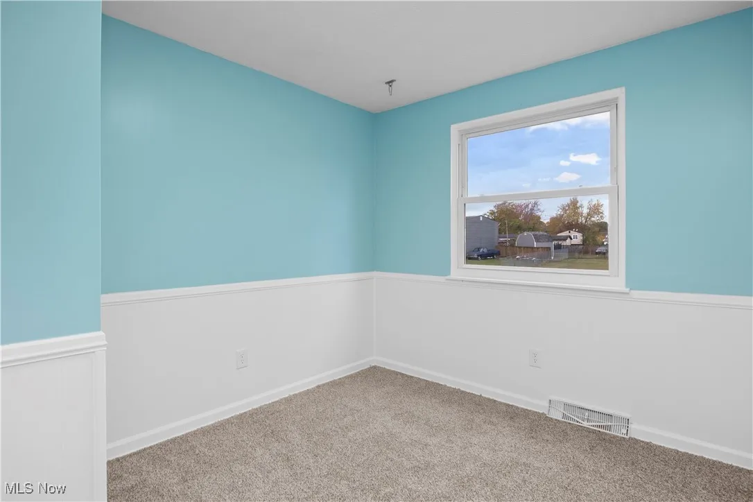 Carpeted spare room featuring baseboards