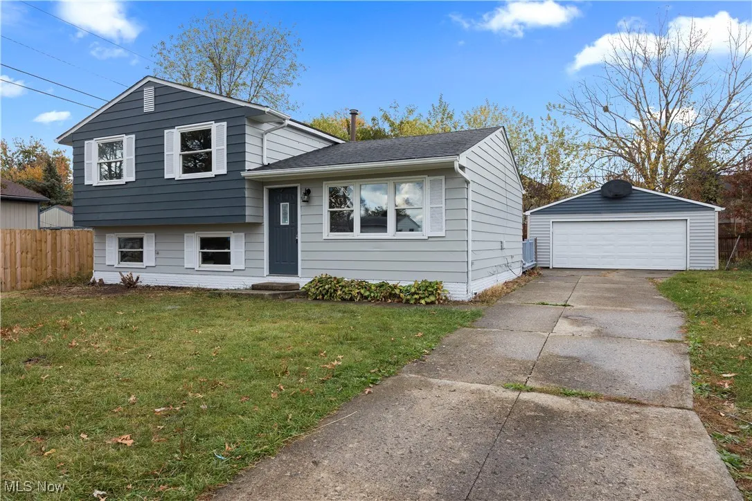 Split level home featuring a garage, an outbuilding, and a shingled roof