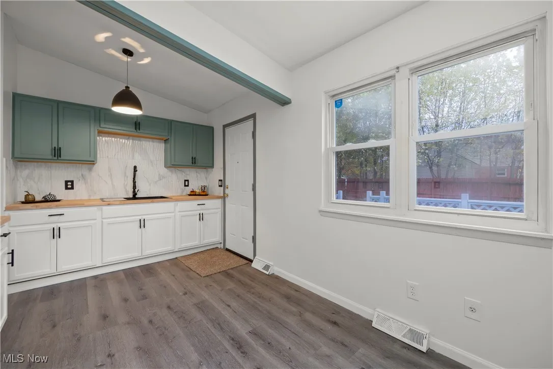 Kitchen with decorative backsplash, lofted ceiling, pendant lighting, light wood-style flooring, and butcher block counters