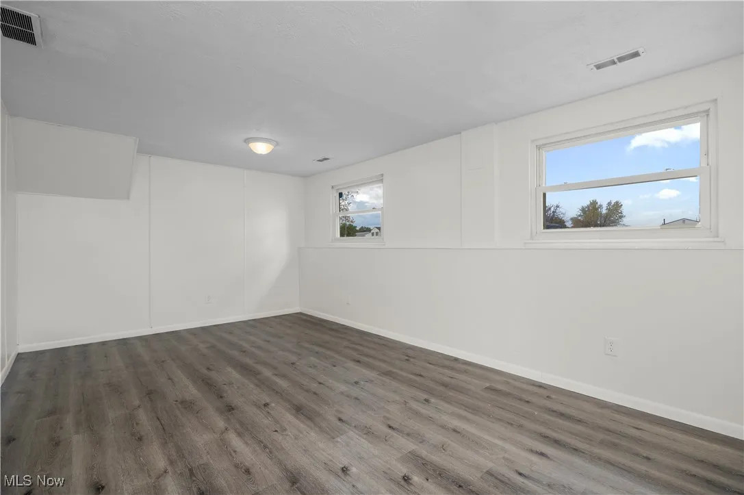 Unfurnished room featuring dark wood-style flooring and baseboards