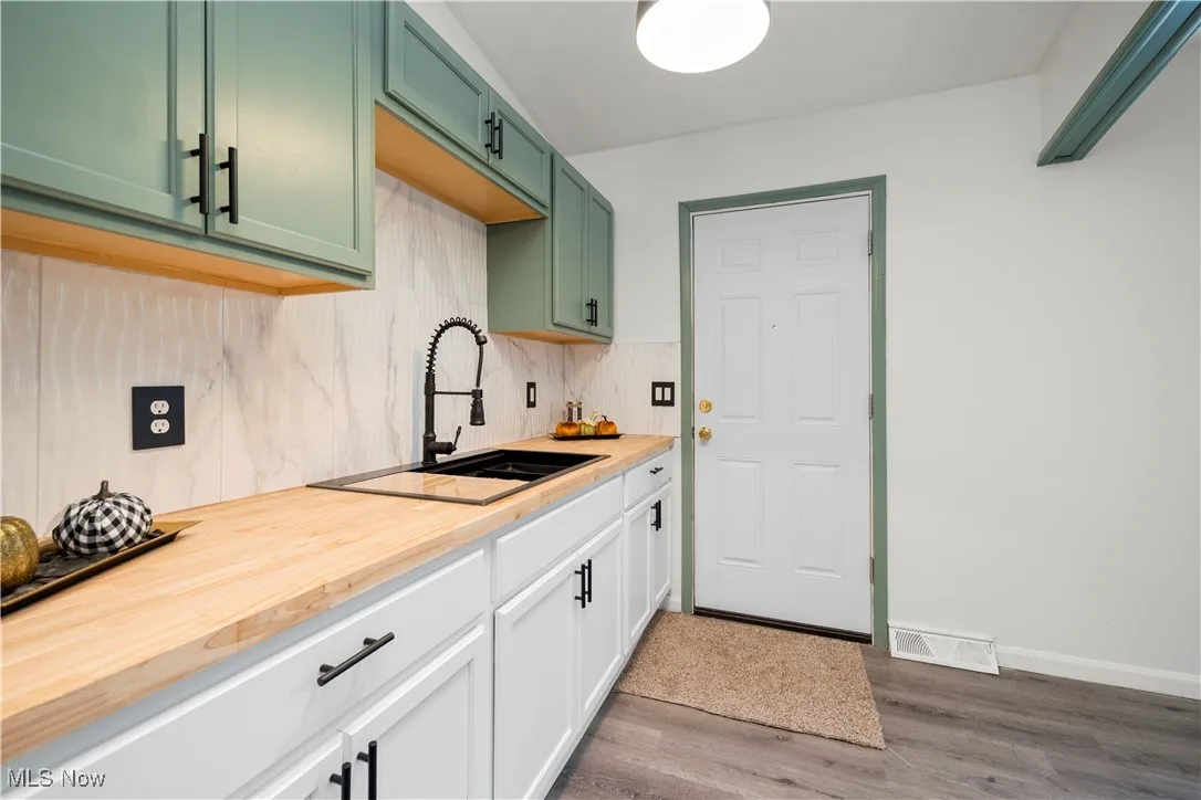 Kitchen with dark wood-style floors, decorative backsplash, and wooden counters