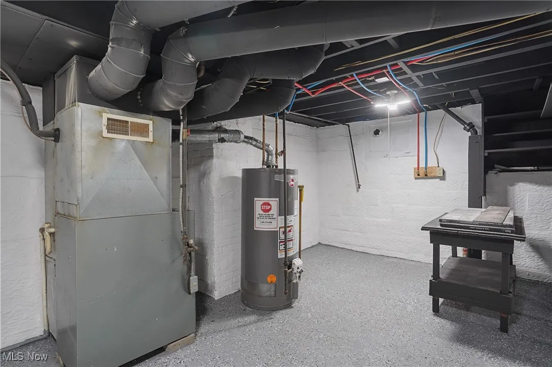 Unfinished below grade area with heating unit and gas water heater
