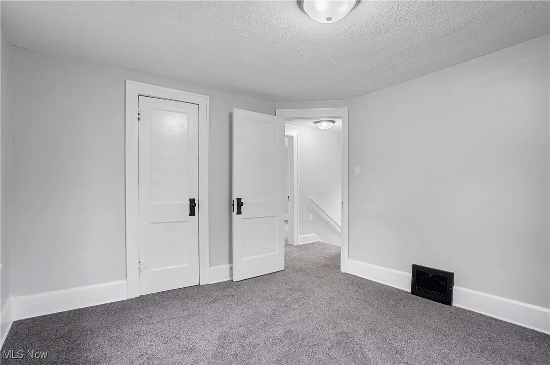 Unfurnished bedroom with a textured ceiling and carpet flooring