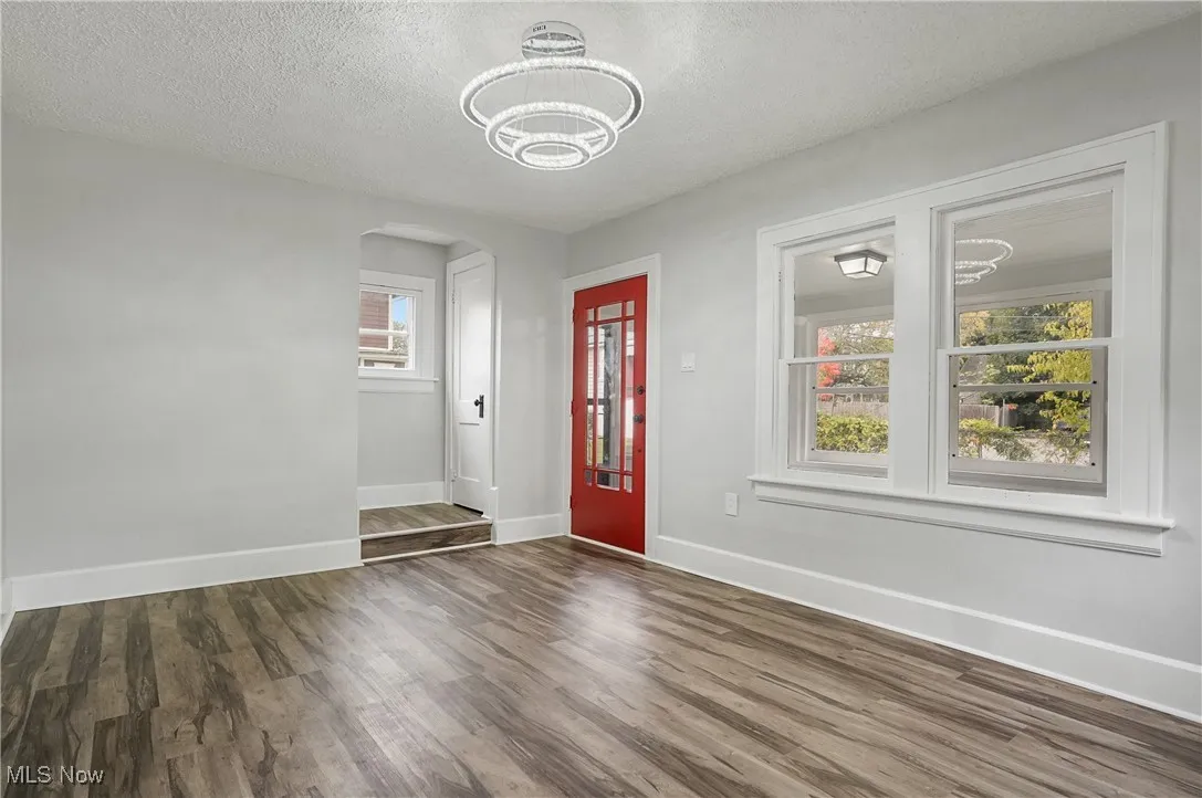 Entrance foyer featuring arched walkways, a textured ceiling, and dark wood-style floors