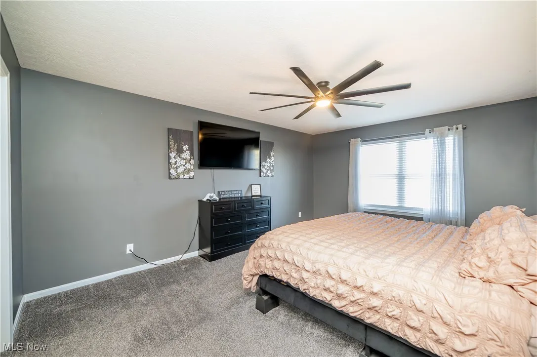 Carpeted bedroom featuring baseboards and a ceiling fan
