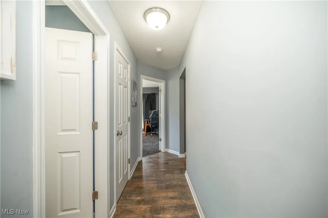Hallway featuring dark wood-style floors and a desk
