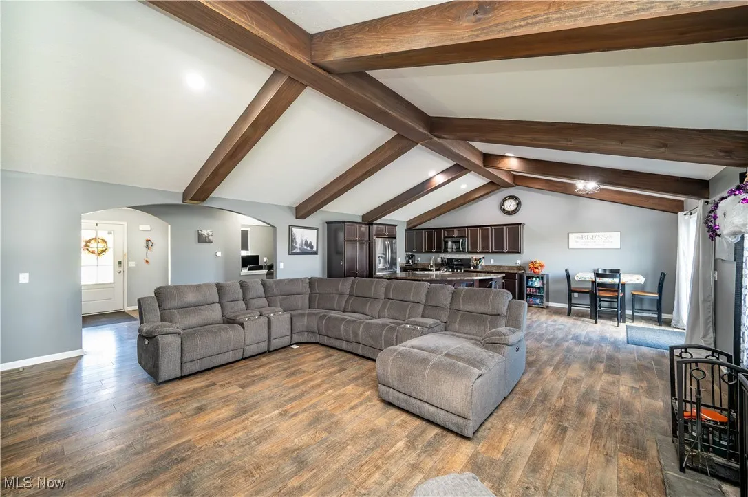 Living room with arched walkways and dark wood-style floors