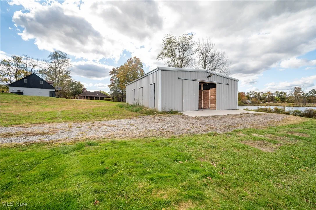 View of pole building with a yard and a water view