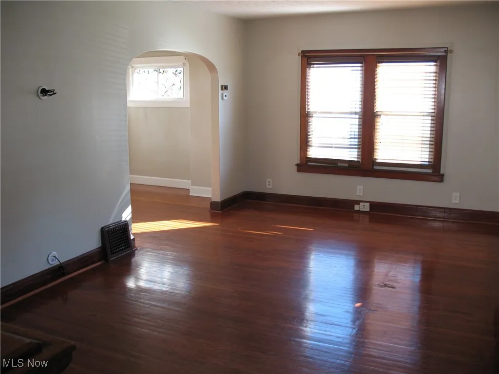 Empty room featuring arched walkways and dark wood finished floors