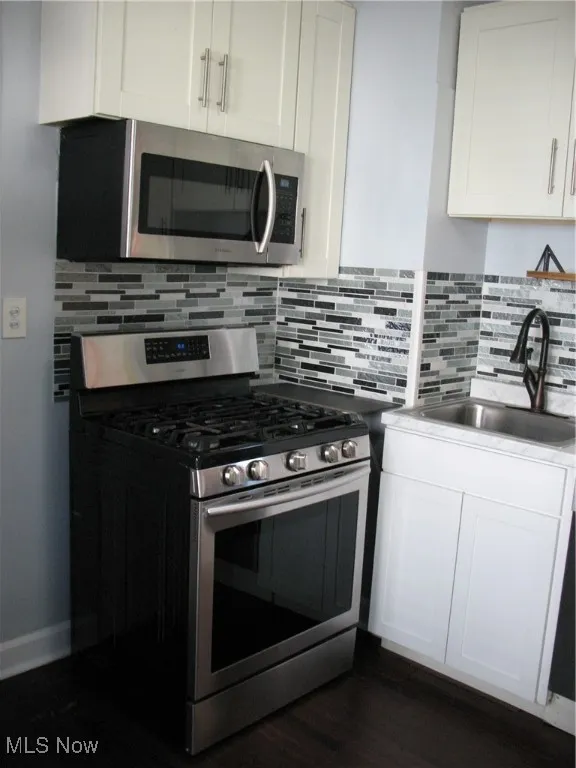 Kitchen featuring stainless steel range, white cabinetry, tasteful backsplash, and dark wood finished floors