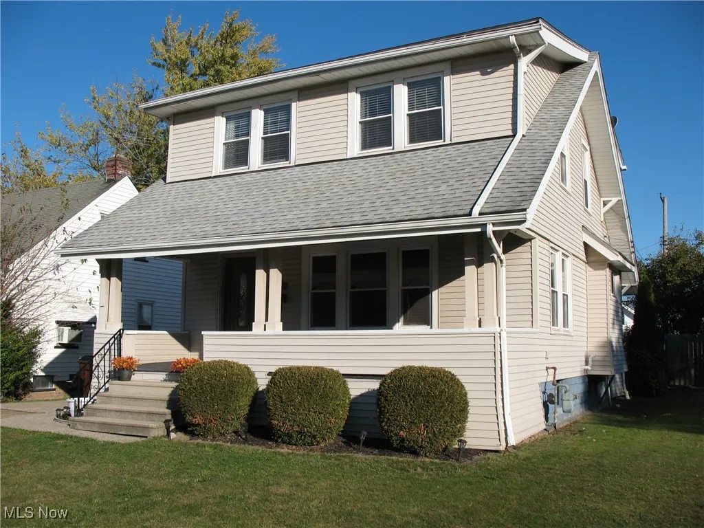 View of front facade with covered porch, a front lawn, and a shingled roof