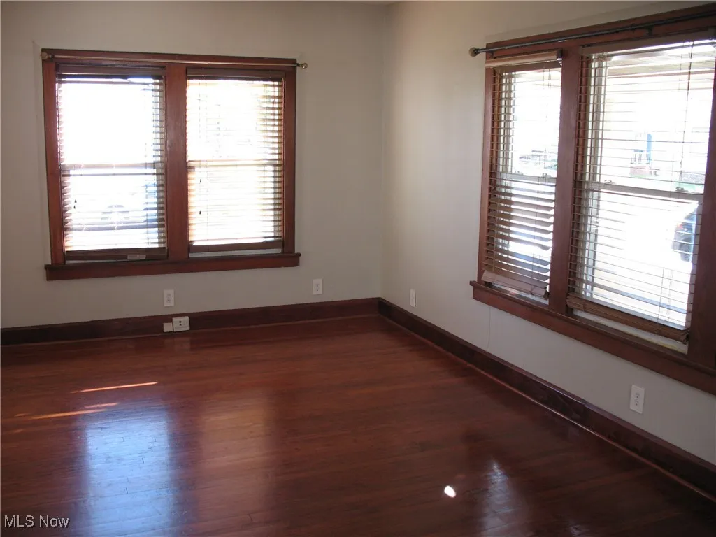 Empty room featuring baseboards and dark wood finished floors
