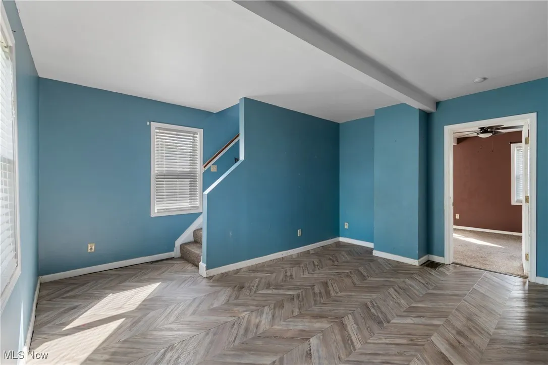 Living room with beamed ceiling, stairway, and a ceiling fan