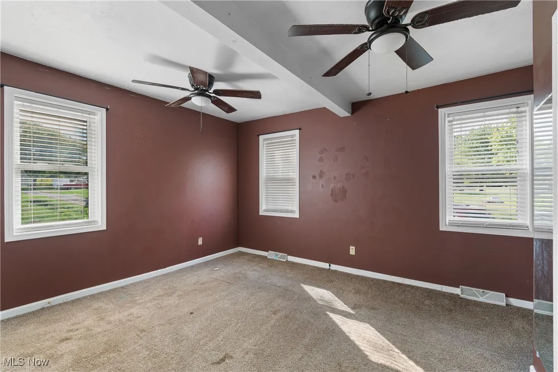 Bedroom featuring beam ceiling, light carpet, and ceiling fan