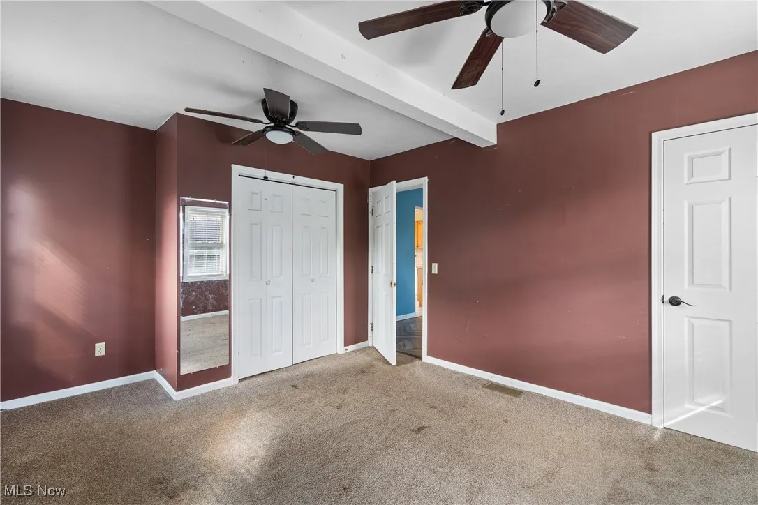 Bedroom with beamed ceiling, carpet, ceiling fan, and a closet