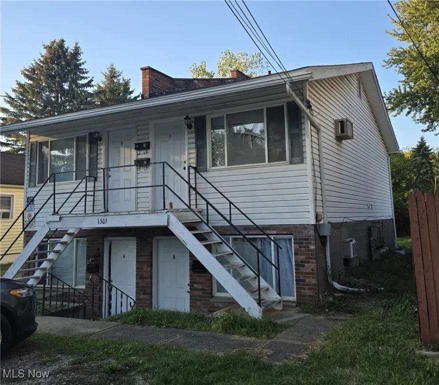 View of front of property featuring stairway, a chimney, and brick siding