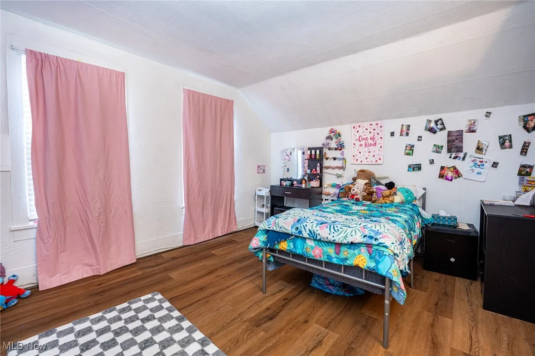 Bedroom with dark wood-style floors and lofted ceiling