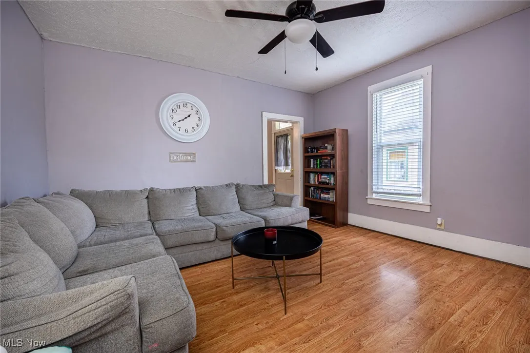 Living area featuring light wood-style floors, a textured ceiling, and a ceiling fan