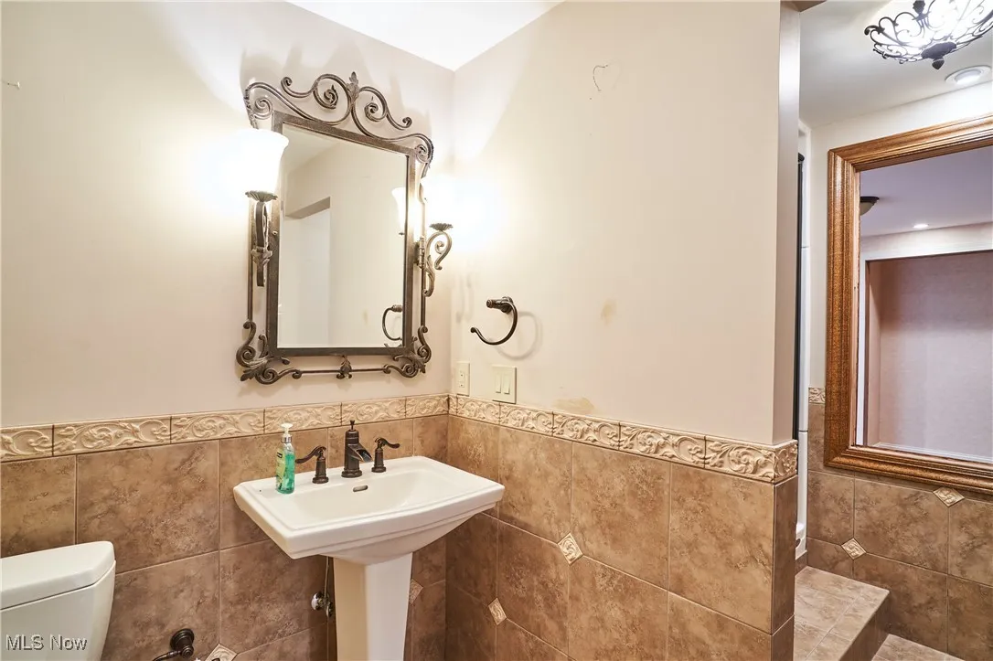 Half bath featuring tile walls and a wainscoted wall
