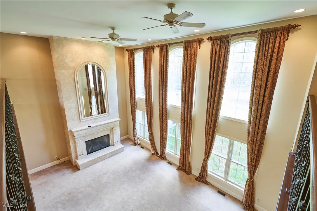 Great room with  two storied of windows and floor to ceiling with a hand  crafted travertine marble mantle gas fireplace.