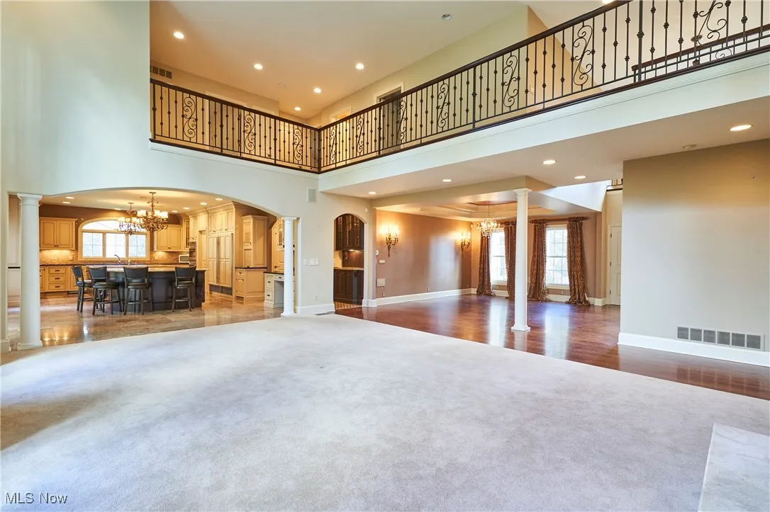 Spacious living area featuring decorative columns, a high ceiling with recessed lighting, and arched walkways.