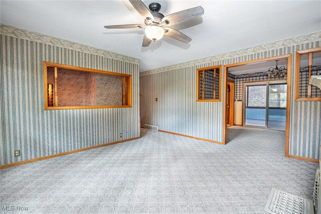 Empty room with wallpapered walls, carpet, and a ceiling fan