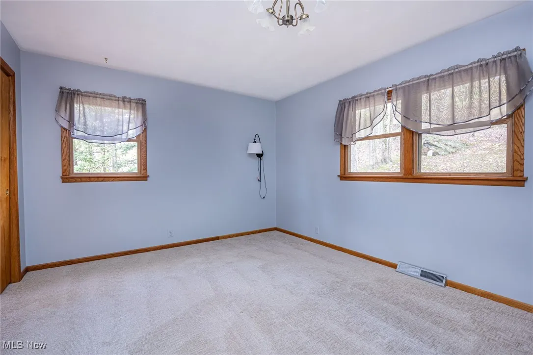 Unfurnished room featuring carpet floors and a chandelier