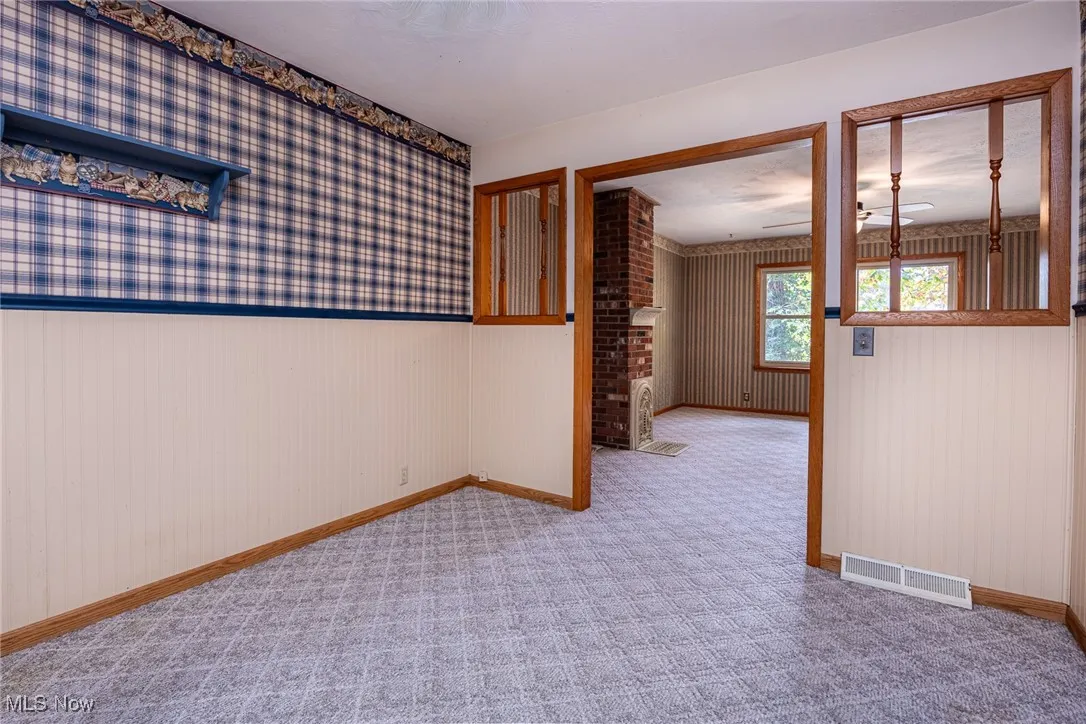 Carpeted empty room featuring wallpapered walls and baseboards