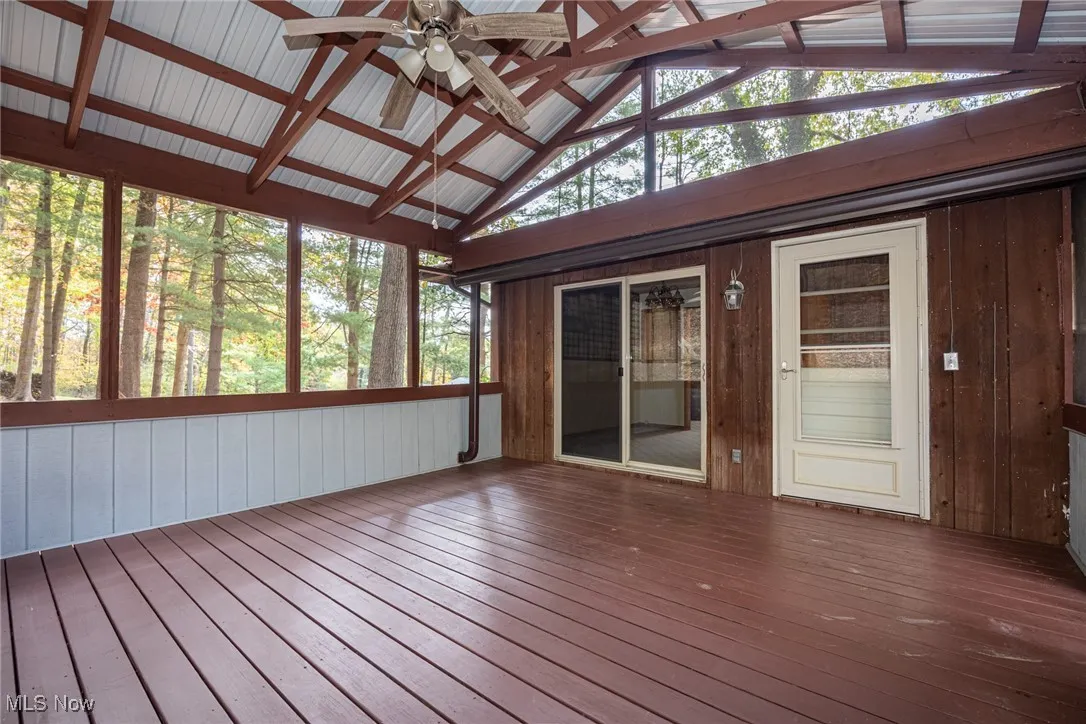 Unfurnished sunroom with a deck, vaulted ceiling, and a ceiling fan