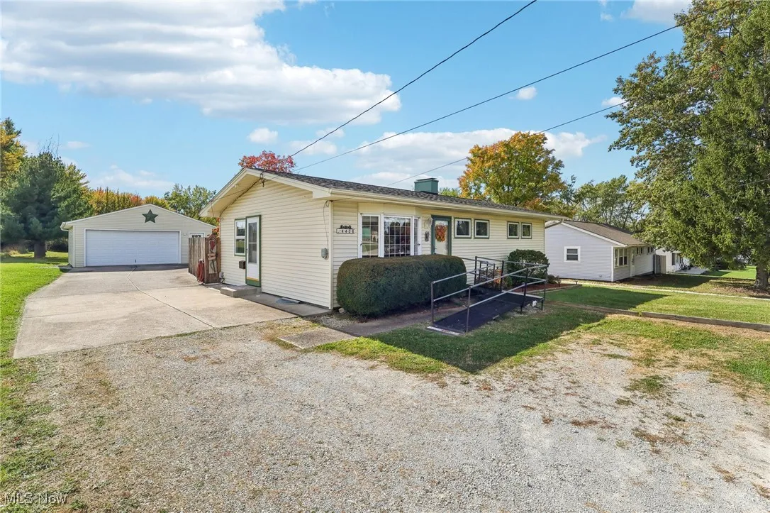 Ranch-style home with a detached garage, an outbuilding, a front lawn, and a chimney