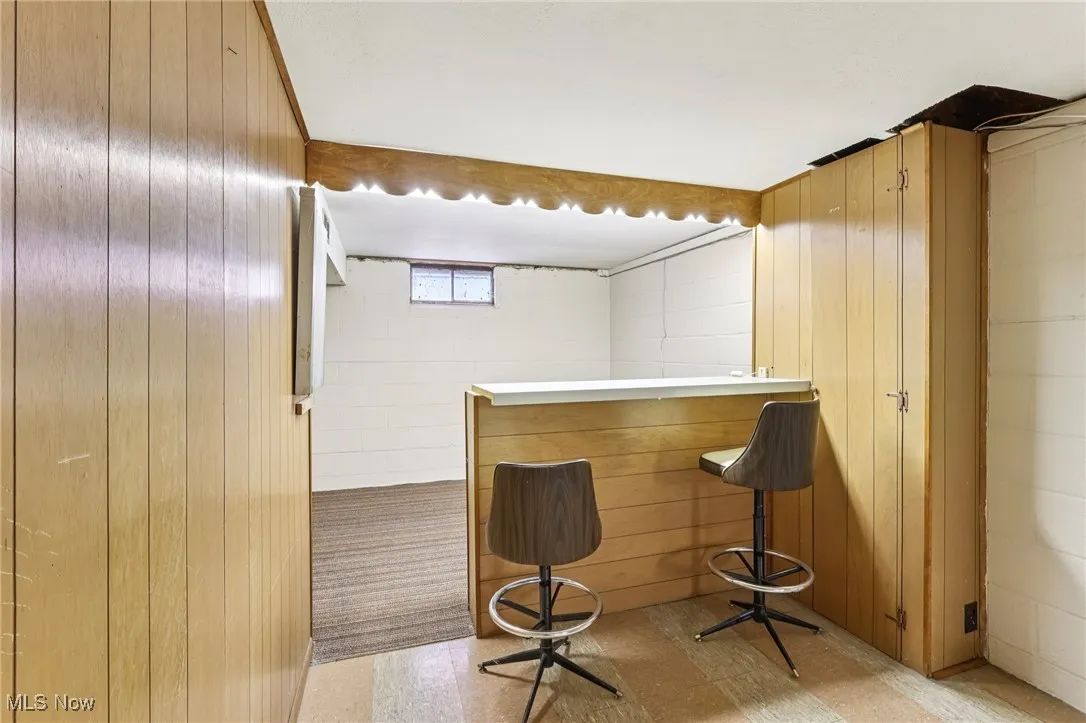 Indoor dry bar with wooden walls and light countertops