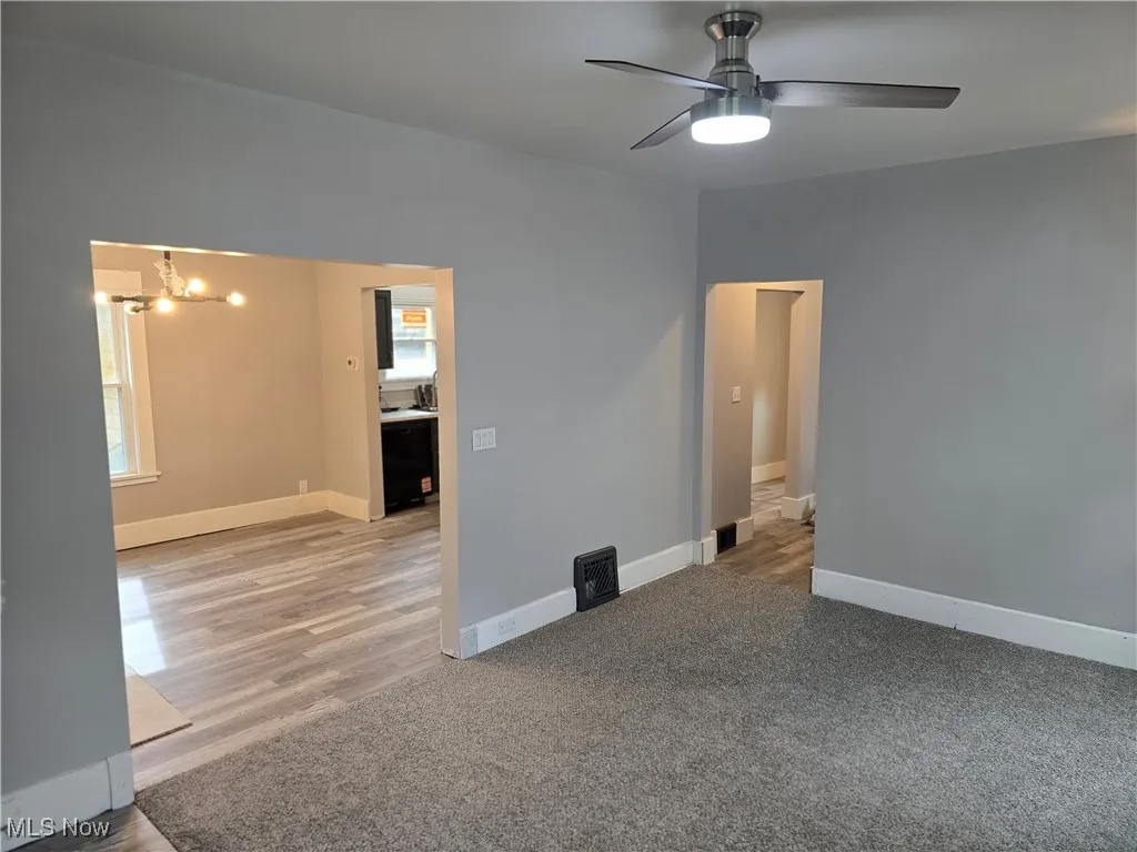 Spare room with a chandelier, light carpet, ceiling fan, and light wood-style floors