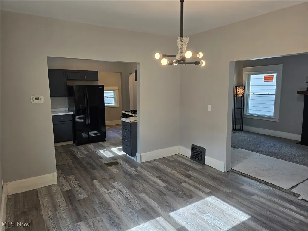 Unfurnished dining area featuring a chandelier and dark wood finished floors