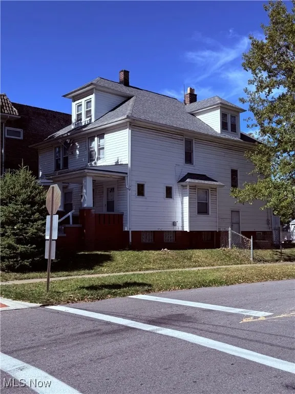 View of side of home featuring a yard, a chimney, 2025 Roof and Side Entrance ~