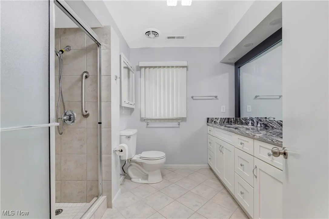 Full bath with granite vanity, a shower stall, and light tile patterned flooring