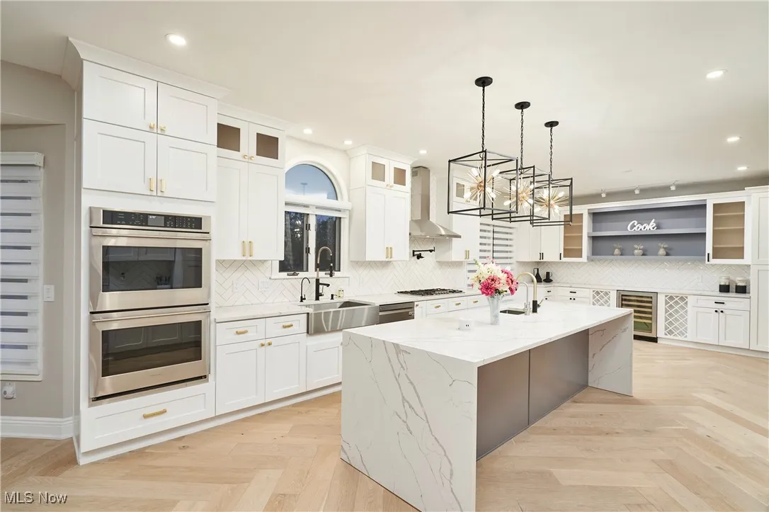 Kitchen with glass insert cabinets, stainless steel double oven, white cabinetry, pendant lighting, and light stone counters