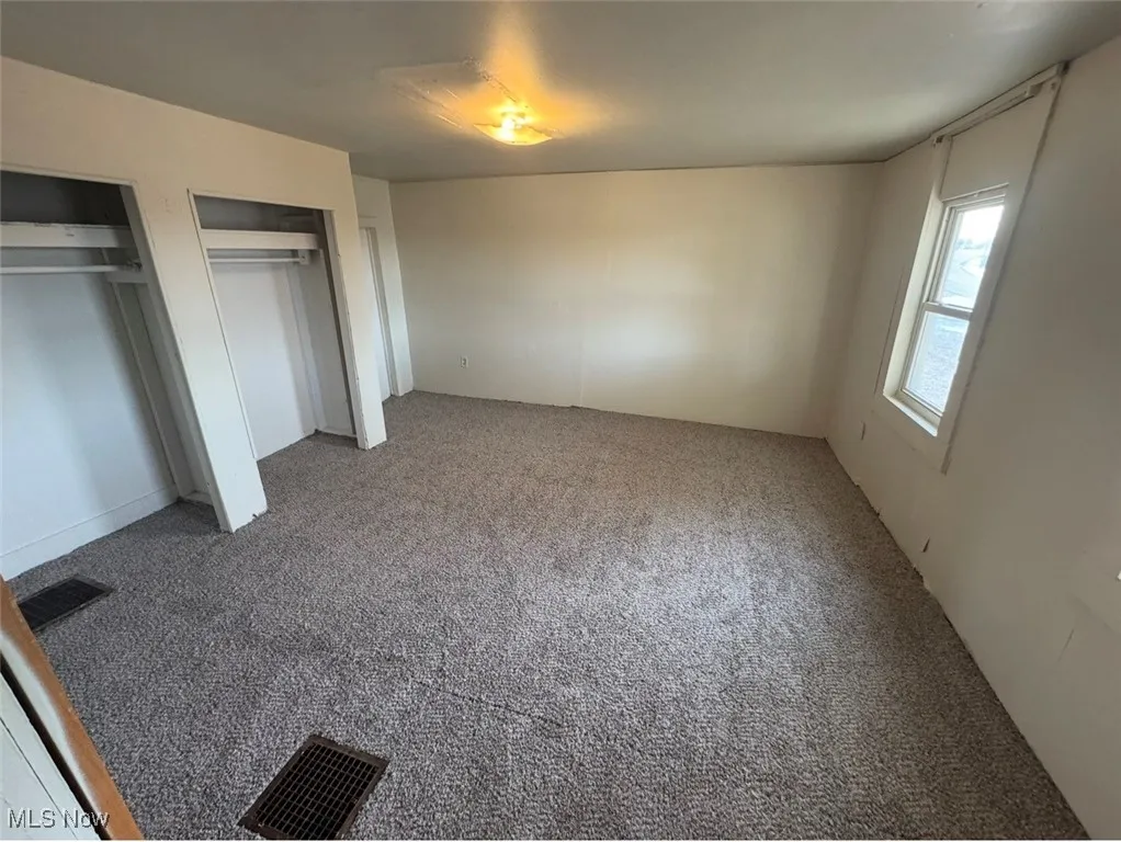 Unfurnished bedroom featuring multiple closets and carpet