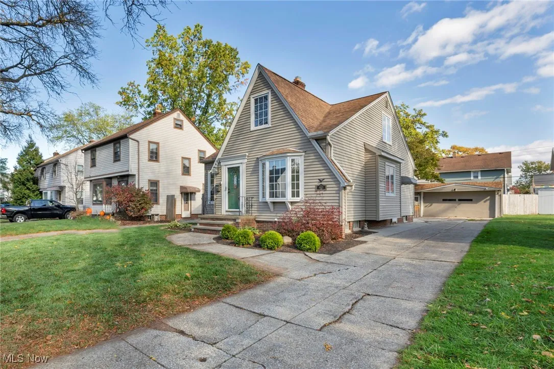 View of front of house featuring a front yard, a detached garage, and a chimney