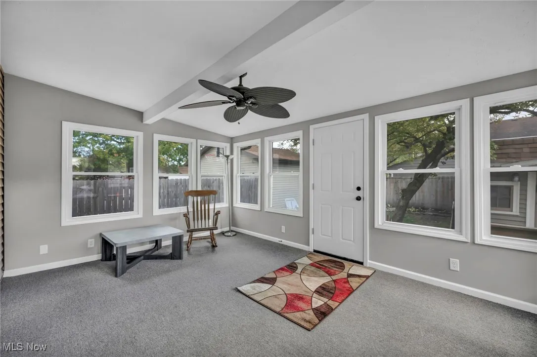 Sitting room featuring beamed ceiling, ceiling fan, and carpet