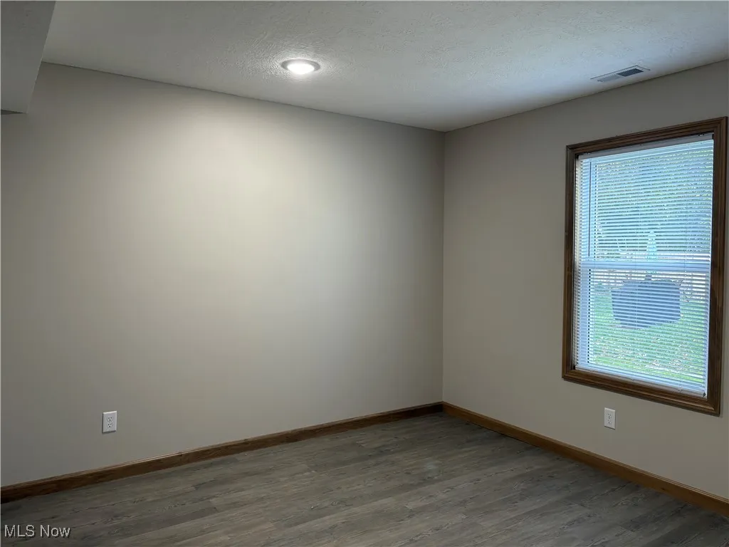 Unfurnished room featuring wood finished floors and a textured ceiling